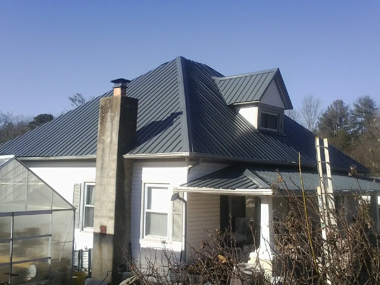 Dark blue standing seam metal roof on a white farmhouse with dormer — Slate & Tile Roof Repair by Roofing Brothers in East Stroudsburg