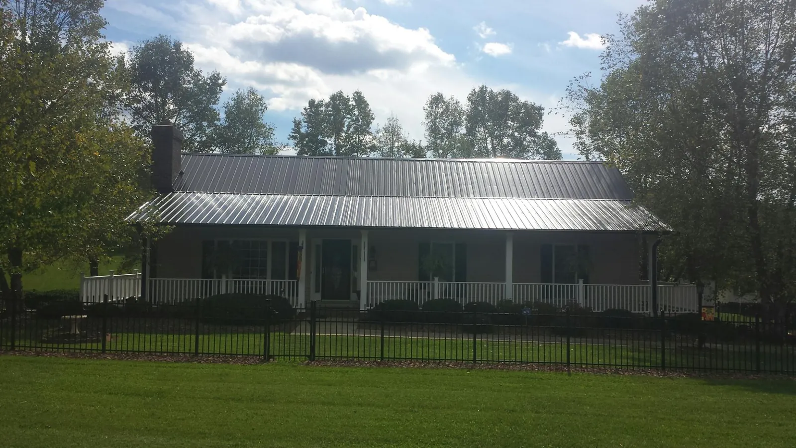 Gray metal roof on a brick ranch with a full width front porch — Gutter Guard Installation work by our crew in East Stroudsburg