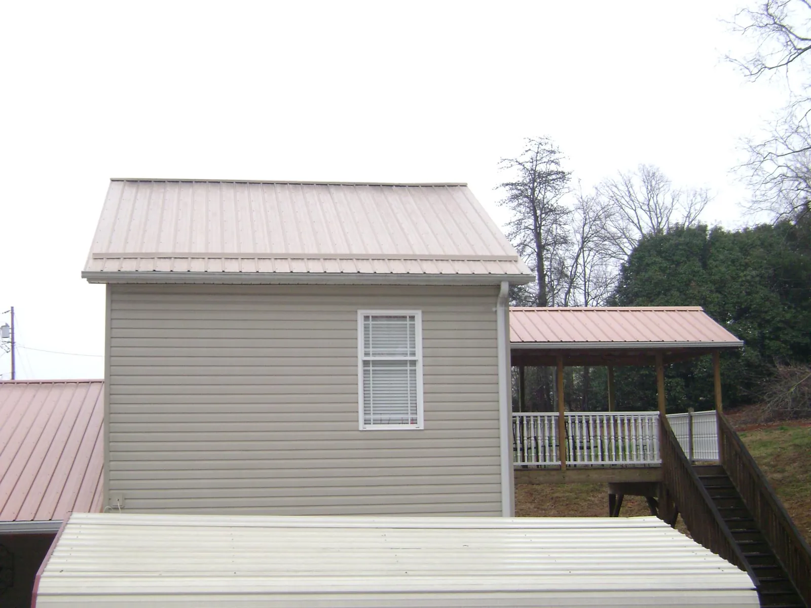 Tan metal roofs on a two story addition and attached porch, from a Roof Replacement job in East Stroudsburg